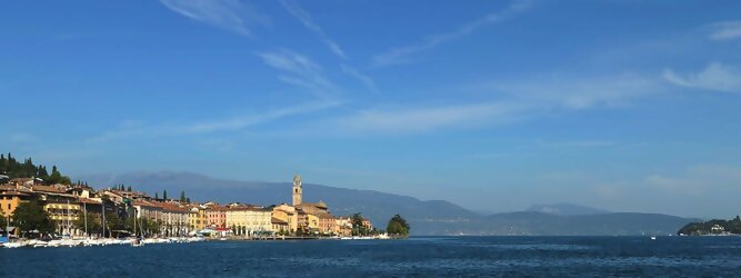 Trip Weekend beliebte Urlaubsziele am Gardasee -  Mit einer Fläche von 370 km² ist der Gardasee der größte See Italiens. Es liegt am Fuße der Alpen und erstreckt sich über drei Staaten: Lombardei, Venetien und Trentino. Die maximale Tiefe des Sees beträgt 346 m, er hat eine längliche Form und sein nördliches Ende ist sehr schmal. Dort ist der See von den Bergen der Gruppo di Baldo umgeben. Du trittst aus deinem gemütlichen Hotelzimmer und es begrüßt dich die warme italienische Sonne. Du blickst auf den atemberaubenden Gardasee, der in zahlreichen Blautönen schimmert - von tiefem Dunkelblau bis zu funkelndem Türkis. Majestätische Berge umgeben dich, während die Brise sanft deine Haut streichelt und der Duft von blühenden Zitronenbäumen deine Nase kitzelt. Du schlenderst die malerischen, engen Gassen entlang, vorbei an farbenfrohen, blumengeschmückten Häusern. Vereinzelt unterbricht das fröhliche Lachen der Einheimischen die friedvolle Stille. Du fühlst dich wie in einem Traum, der nicht enden will. Jeder Schritt führt dich zu neuen Entdeckungen und Abenteuern. Du probierst die köstliche italienische Küche mit ihren frischen Zutaten und verführerischen Aromen. Die Sonne geht langsam unter und taucht den Himmel in ein leuchtendes Orange-rot - ein spektakulärer Anblick.